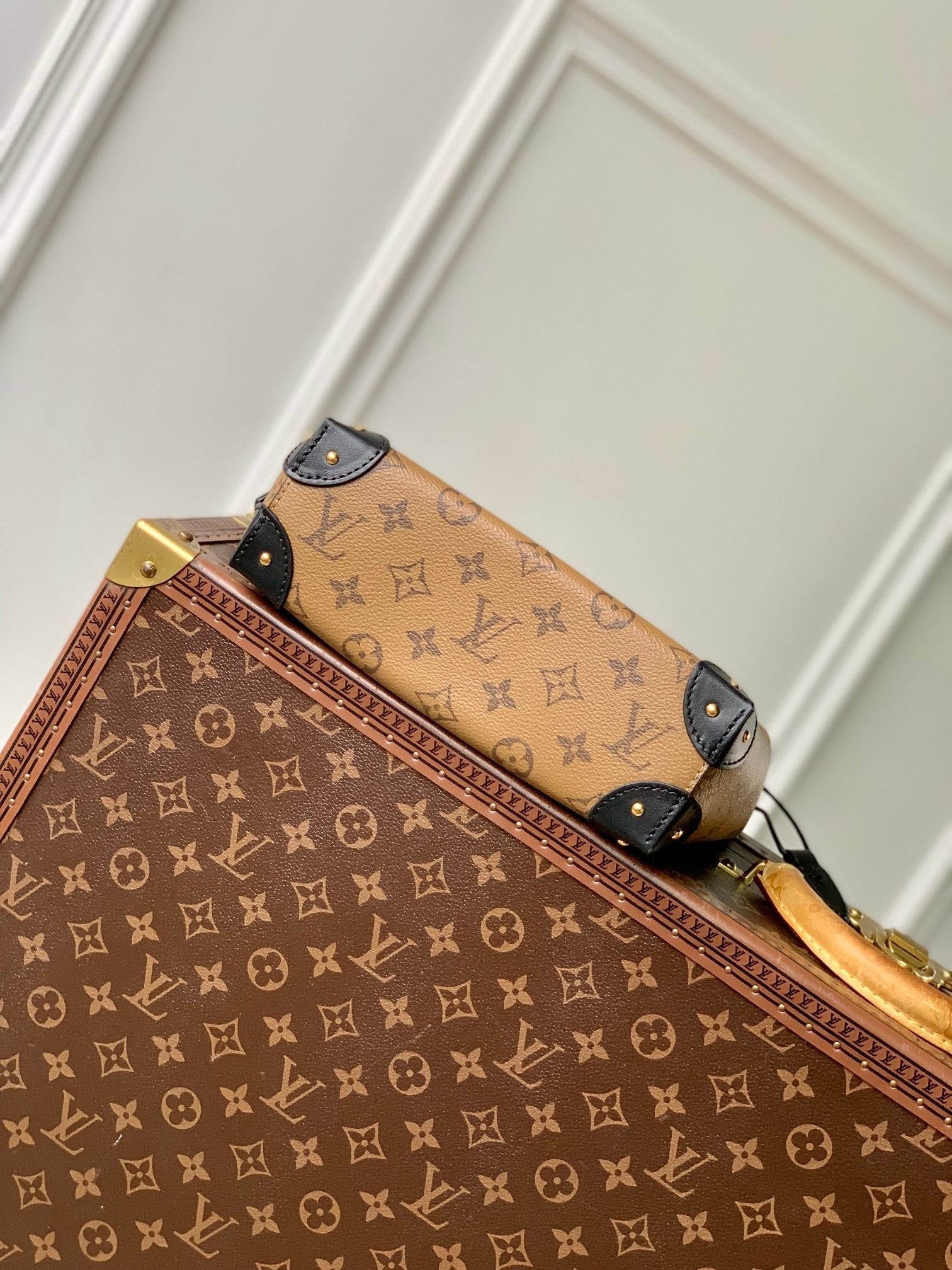 Malle Noé 23 en toile inversée monogrammée marron et quincaillerie dorée